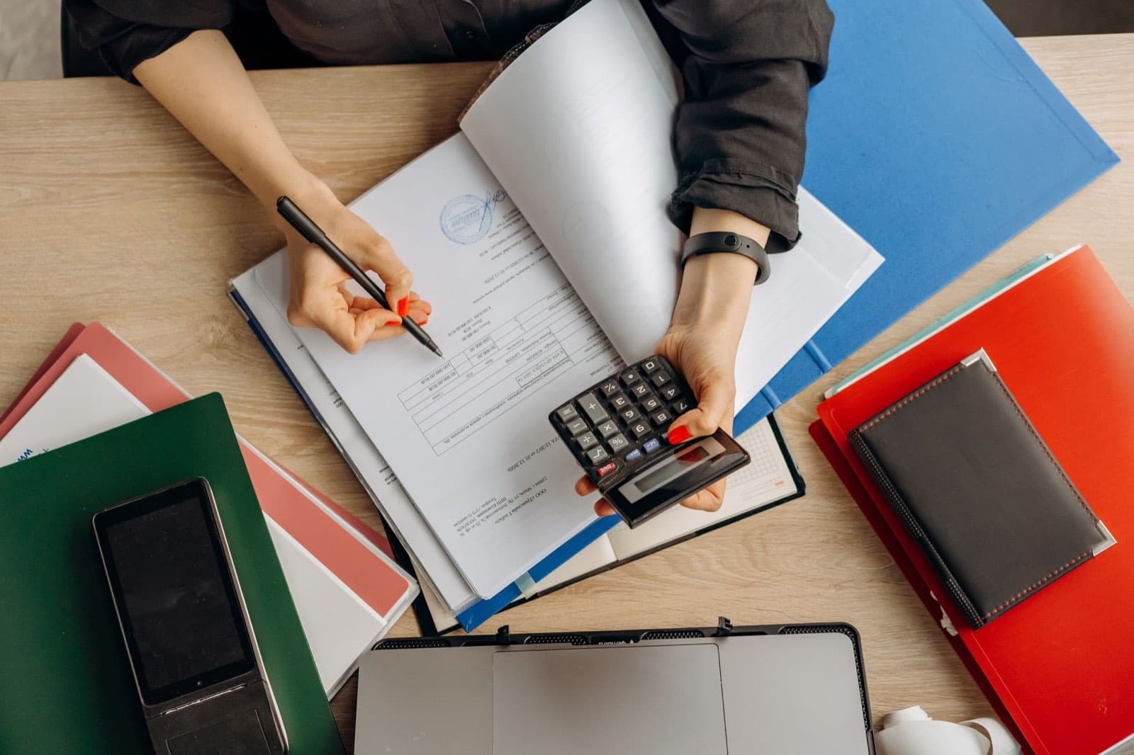 Accountant reviewing financial documents with a calculator at a desk.